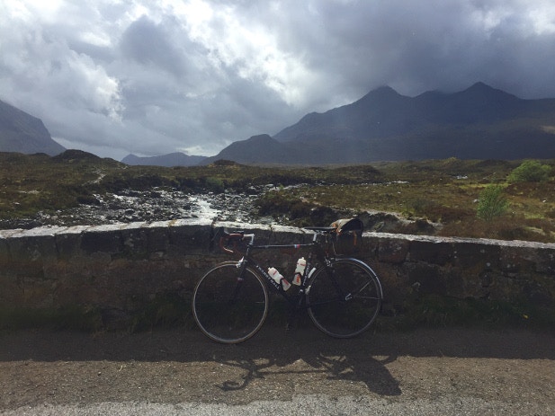 Cycling over a stone bridge overlooking the Cuillin Hills