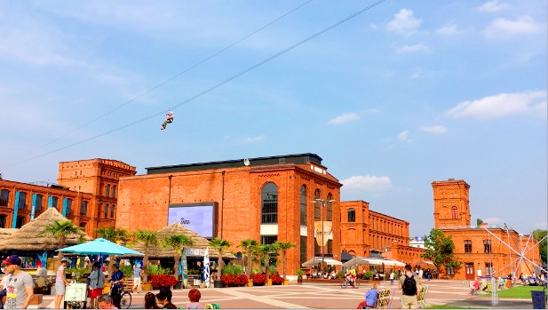 A person zip lining over the Manufaktura complex