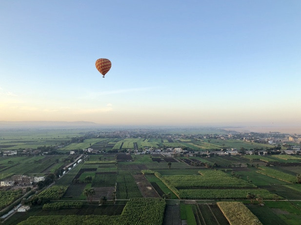 A hot air balloon over the lush green landscapes along the banks of the Nile