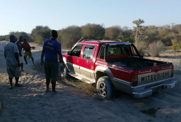 A group of Malagasy men help rescue a 4WD that's got stuck on a sandy road