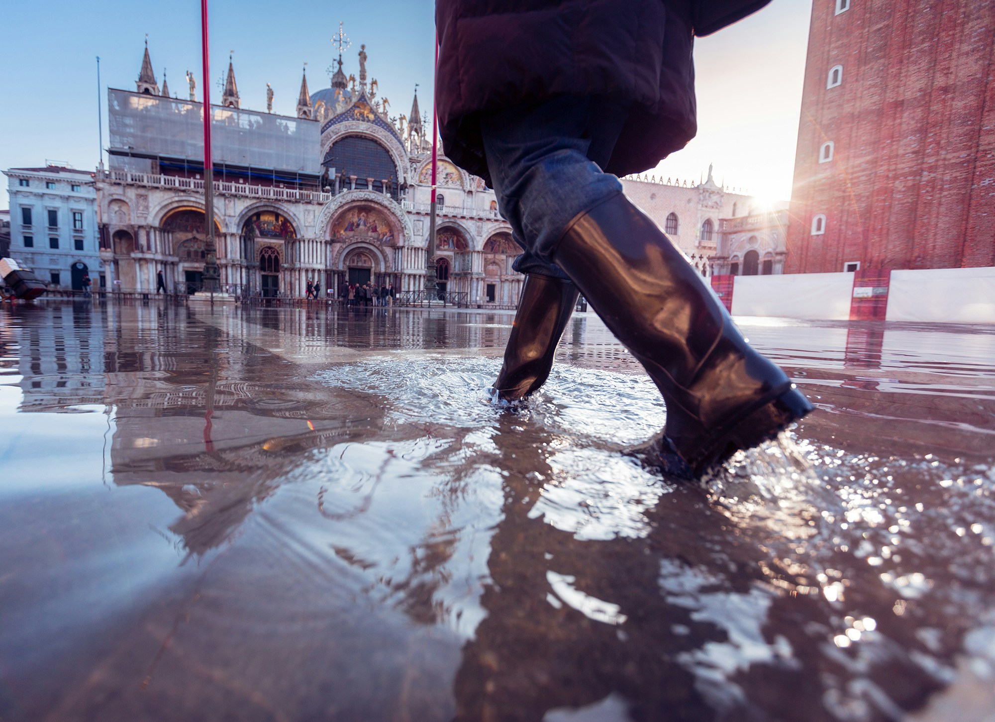 A person in rubber boots walking in Venice's Piazza San Marco © Nullplus / Getty Images