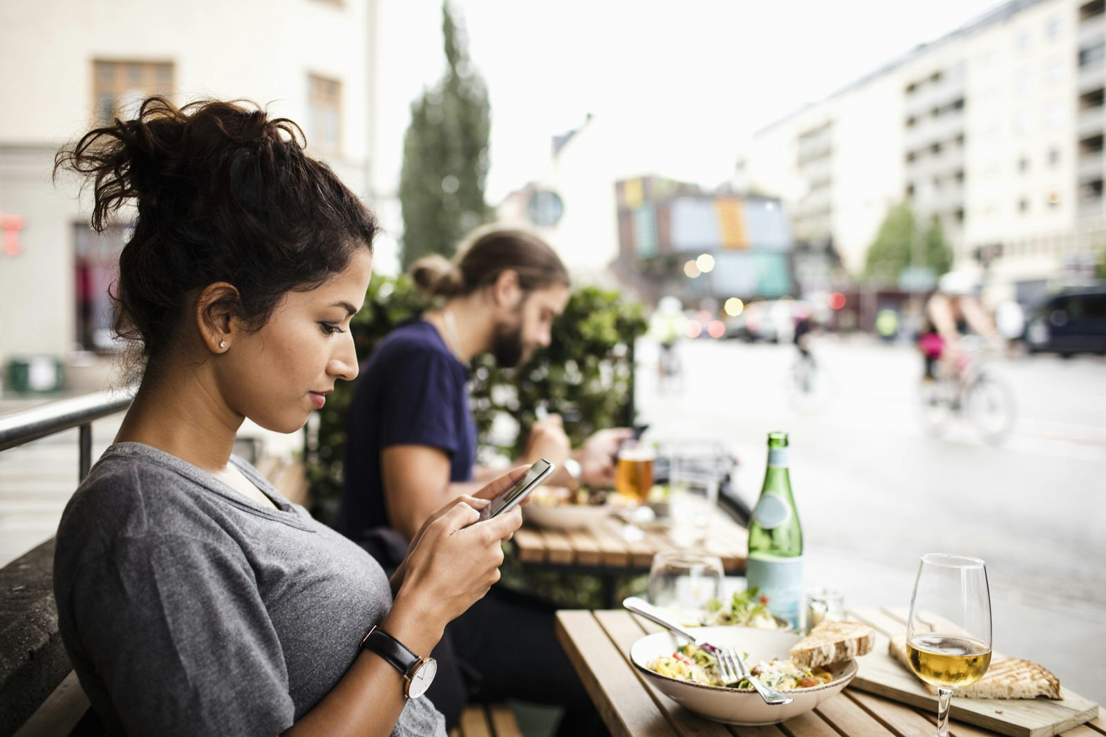 Side view of woman text messaging while having food at sidewalk cafe in city, Sodermalm, Stcokholm.